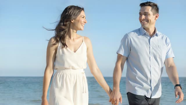 A couple walking hand in hand along the beach
