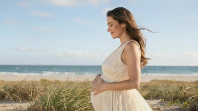 An expectant mother walking through coastal grass beside the water